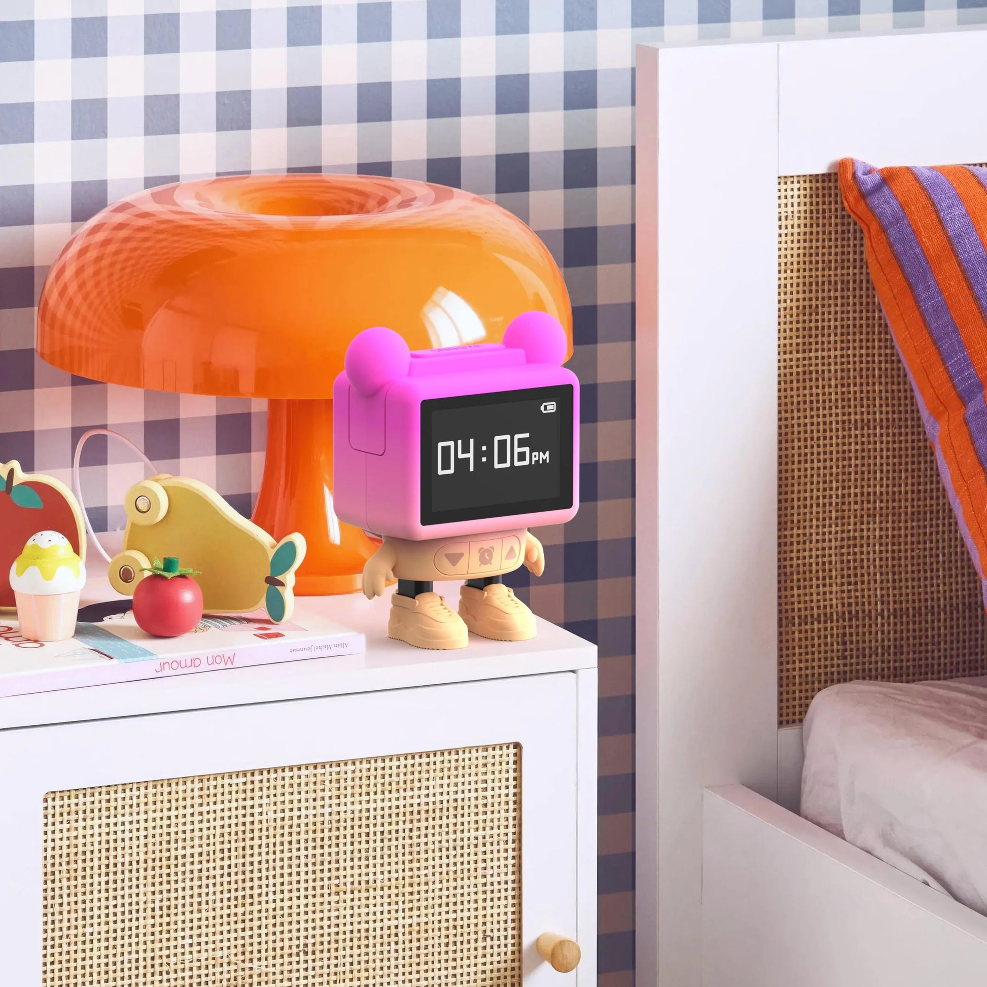 Tańczący budzik dla dzieci w kształcie różowego robota stojący na białej szafce przy łóżku