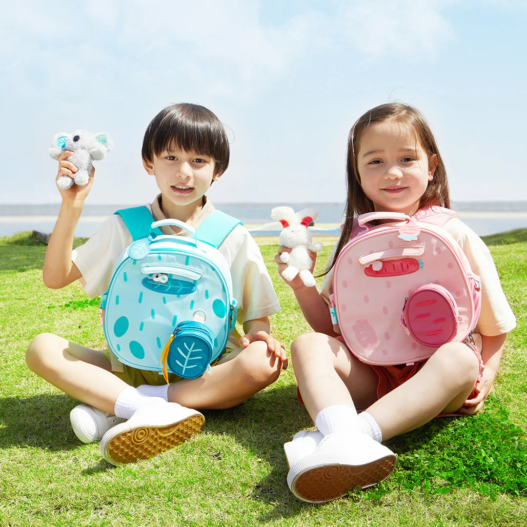 Dzieci z plecakami mideer w kształcie zwierząt na trawie plecak dla dzieci koala różowy i niebieski