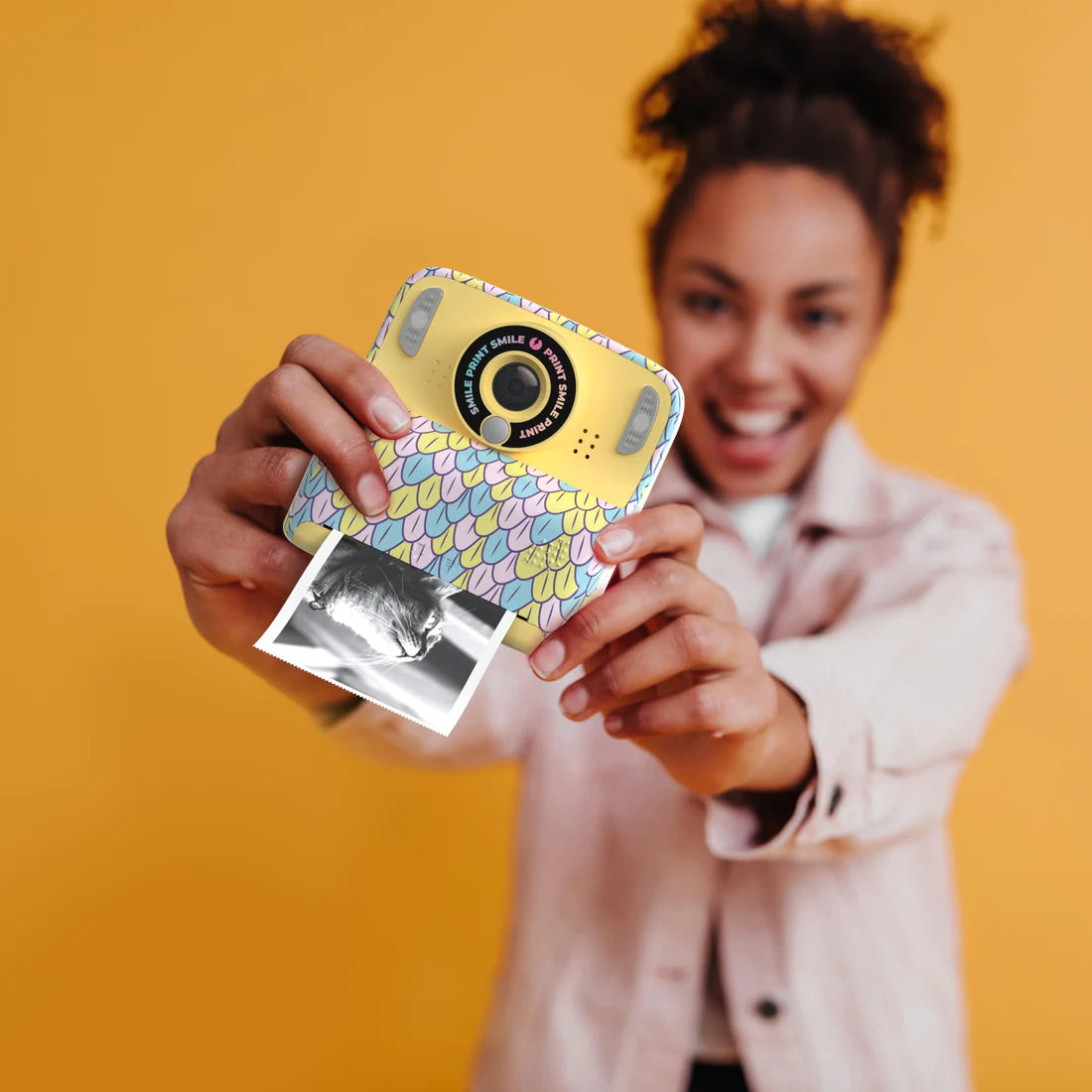 Aparat cyfrowy z drukarką dla dzieci w kolorowej obudowie trzymany przez uśmiechniętą dziewczynkę