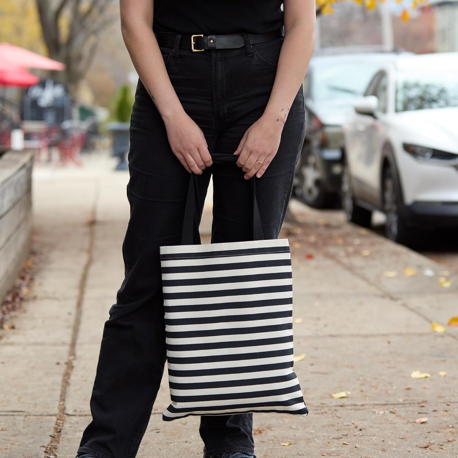 Torba podręczna Warhol Banana w czarno-białe paski trzymana przez osobę na ulicy