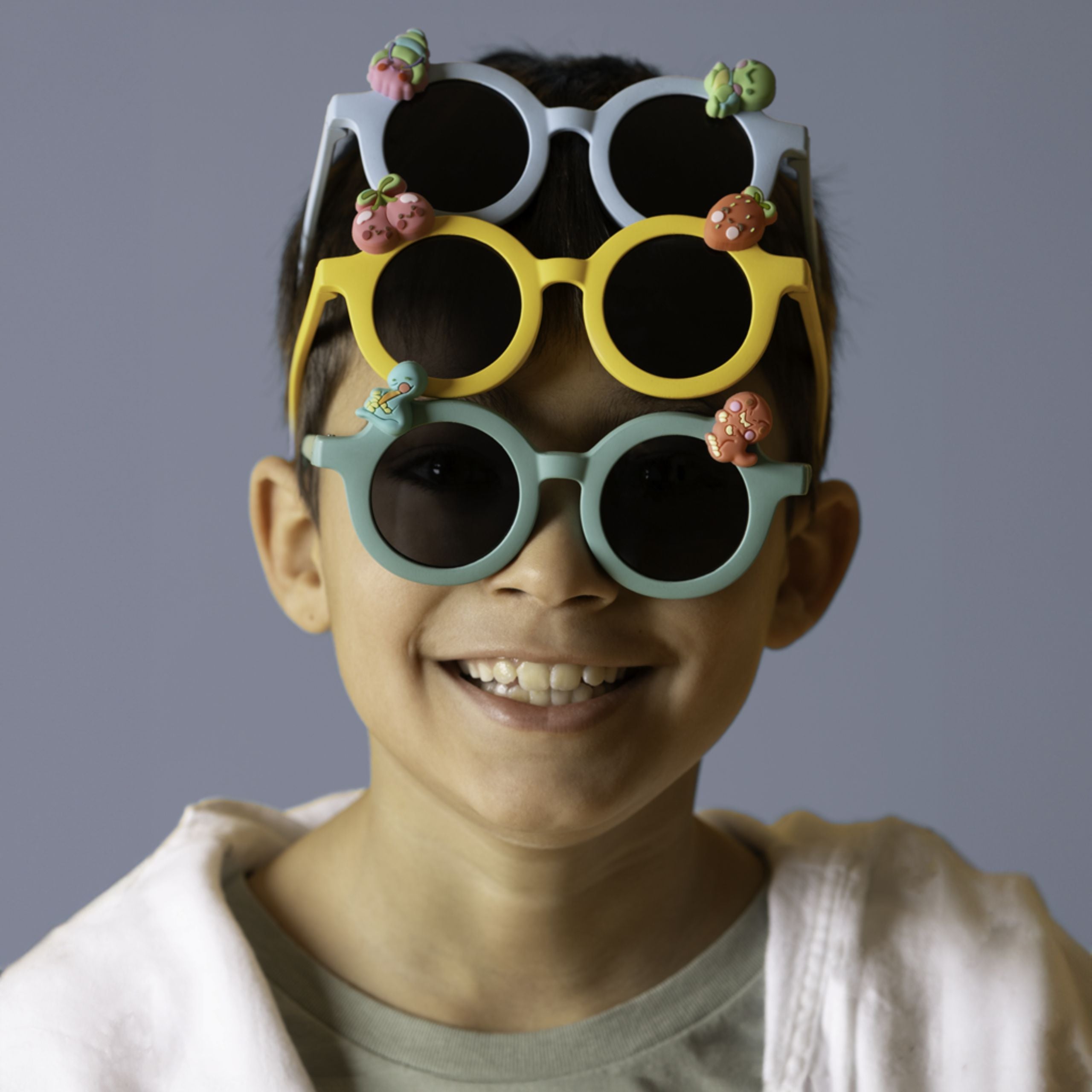 Dziecko w trzech kolorowych okularach przeciwsłonecznych dla dzieci z ozdobami na oprawkach