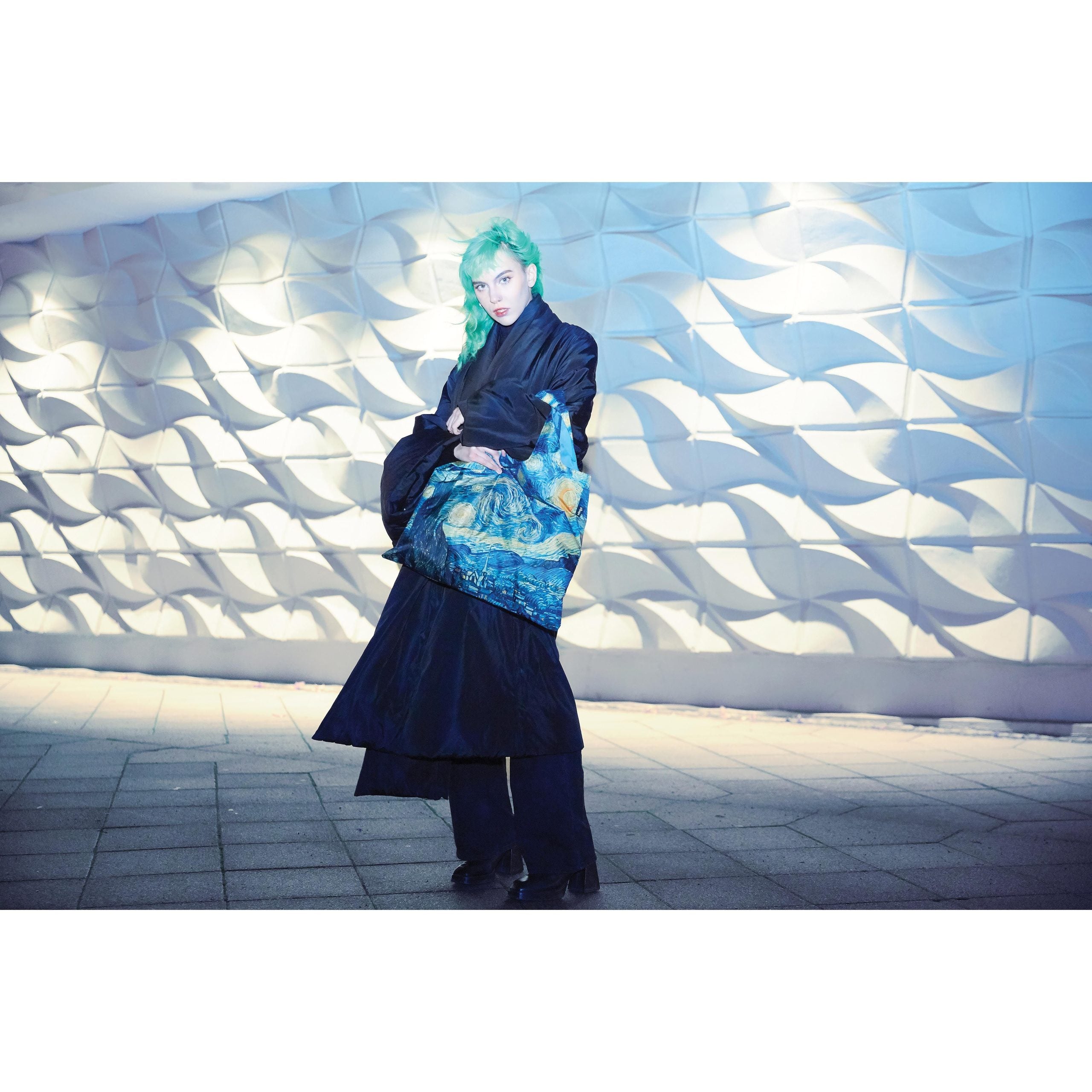 Torba podręczna Vincent van Gogh z nadrukiem Gwiaździstej nocy noszona przez osobę w czarnym płaszczu