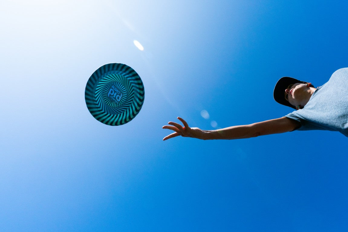 Mężczyzna rzucający latający dysk Waboba Bigwing na tle niebieskiego nieba podczas słonecznego dnia
