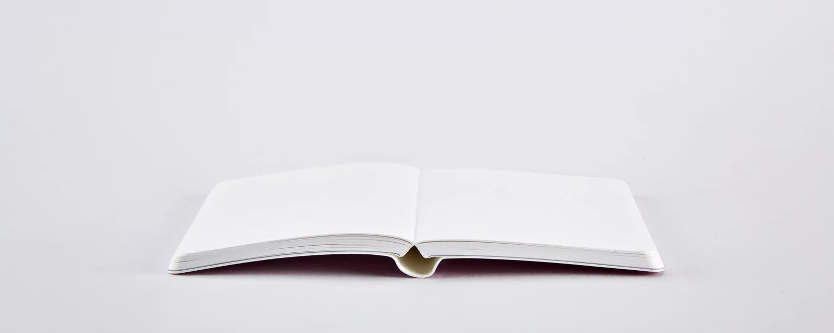 Otwarty pusty notatnik perłowy różowy na białym tle idealny do pisania i rysowania