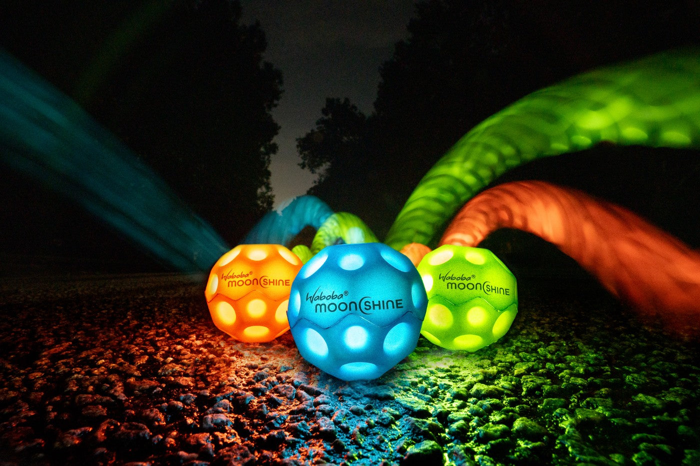 Niebieska piłeczka Waboba Moonshine niebieska świecąca w ciemności na tle innych kolorów