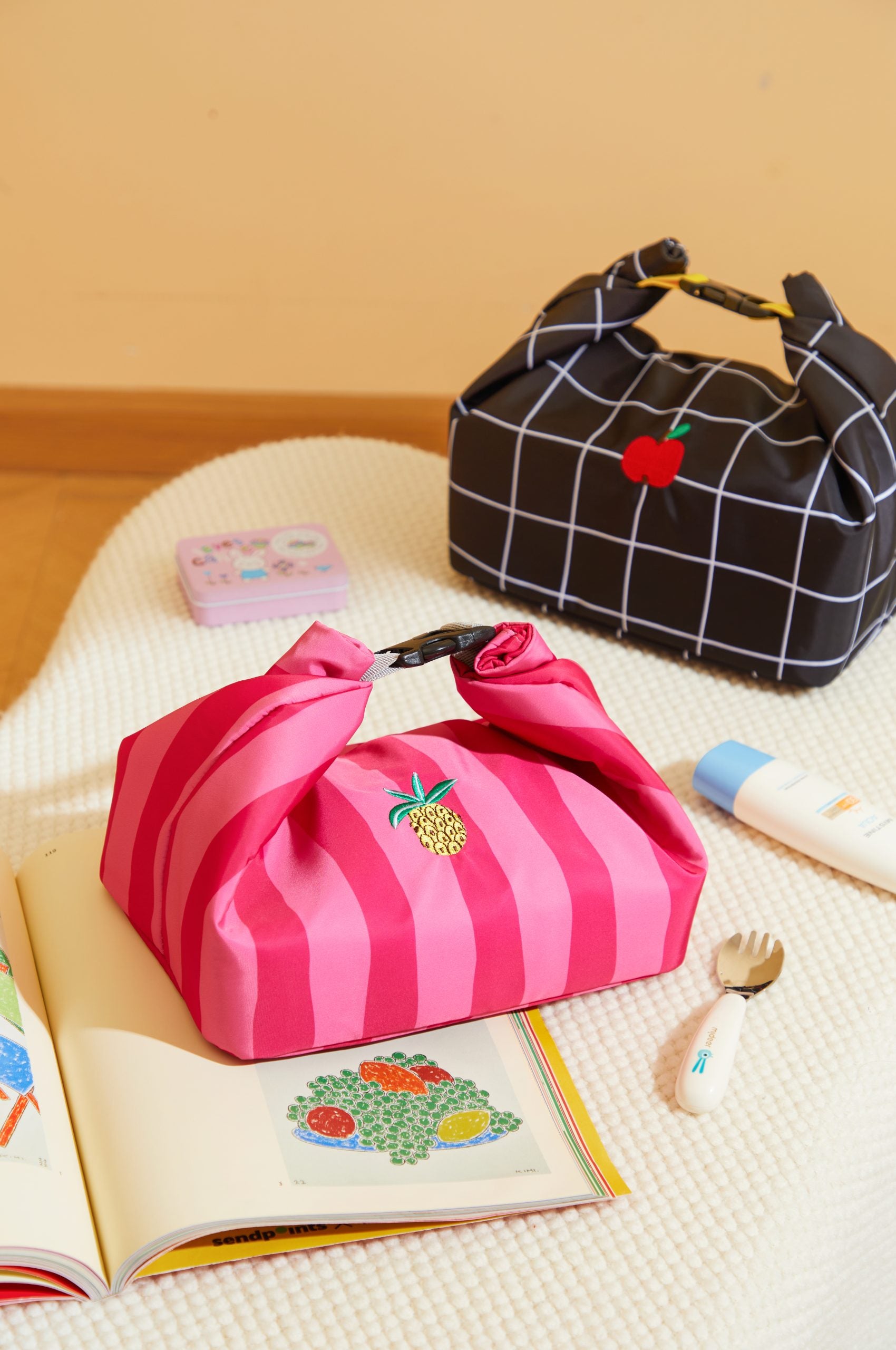 Kolorowa torba na lunch pineapple party w różowe paski z motywem ananasa od MOB na stole