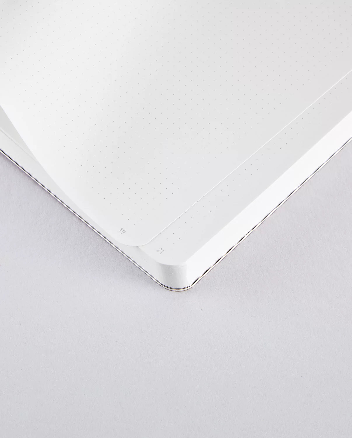 Otwarty notatnik perłowy różowy z perforowanymi kartkami i zaokrąglonymi rogami