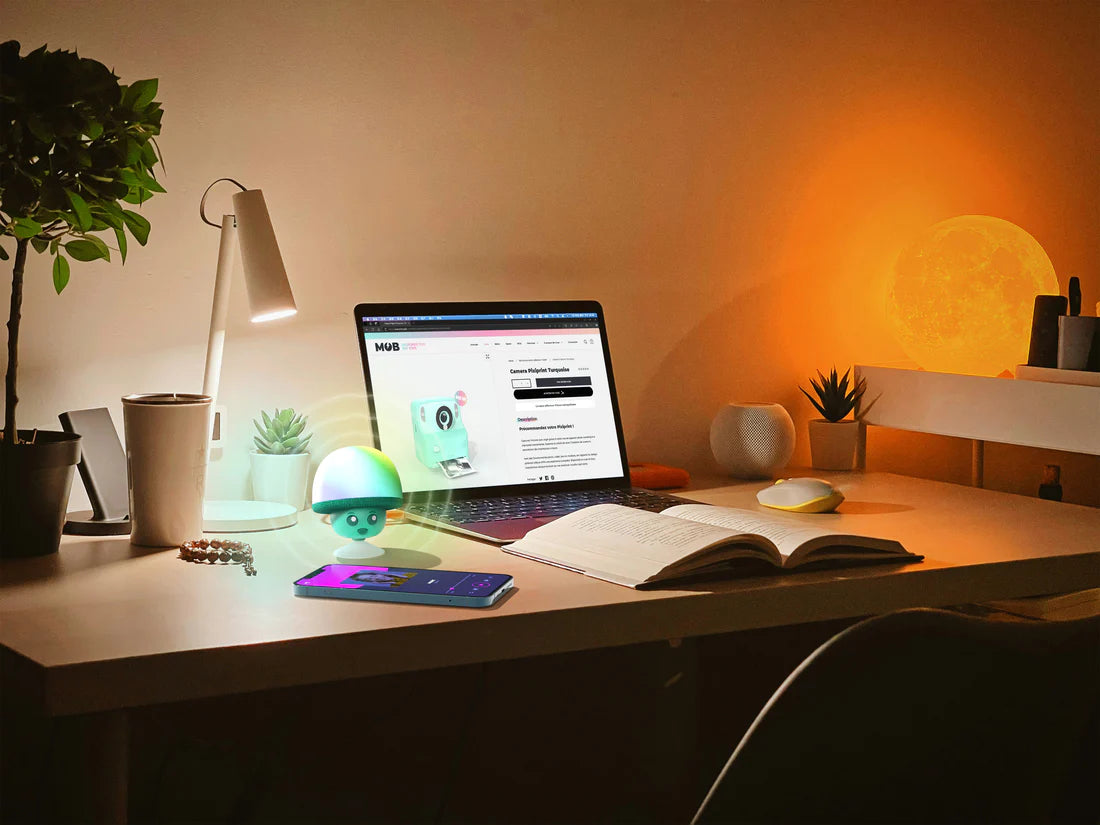 Świecący głośnik bezprzewodowy MOB w kształcie grzyba na biurku obok laptopa i smartfona w przytulnym pokoju