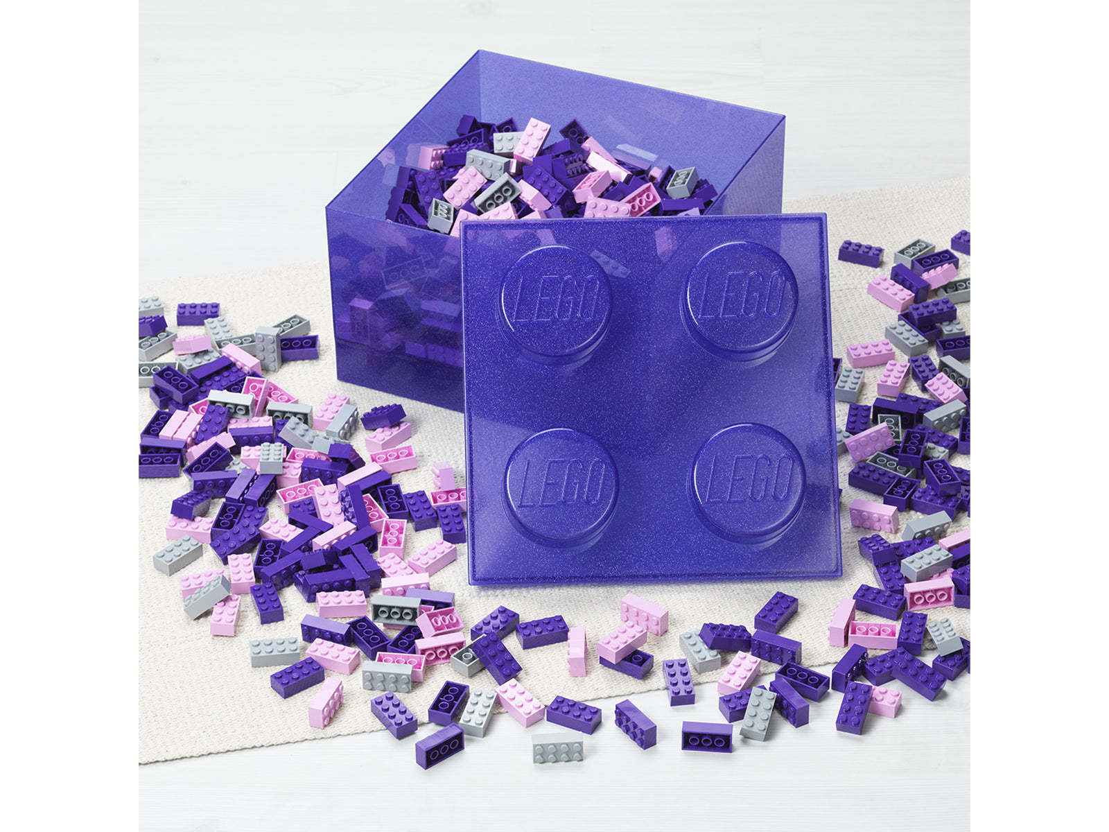 Pojemnik LEGO Brick 4 fioletowy z przezroczystego plastiku wypełniony klockami LEGO w różnych kolorach