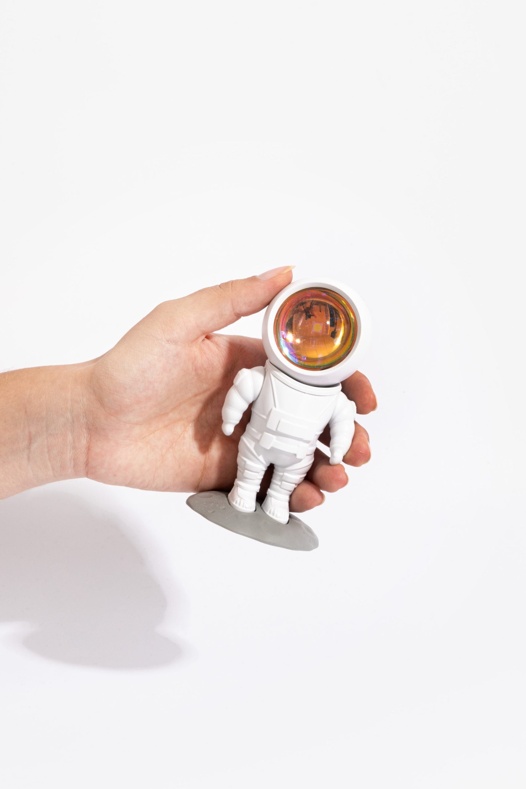Ręka trzyma lampkę projekcyjną astronauta BV JACOB COMPANY w kształcie kosmonauty z pomarańczową szybą