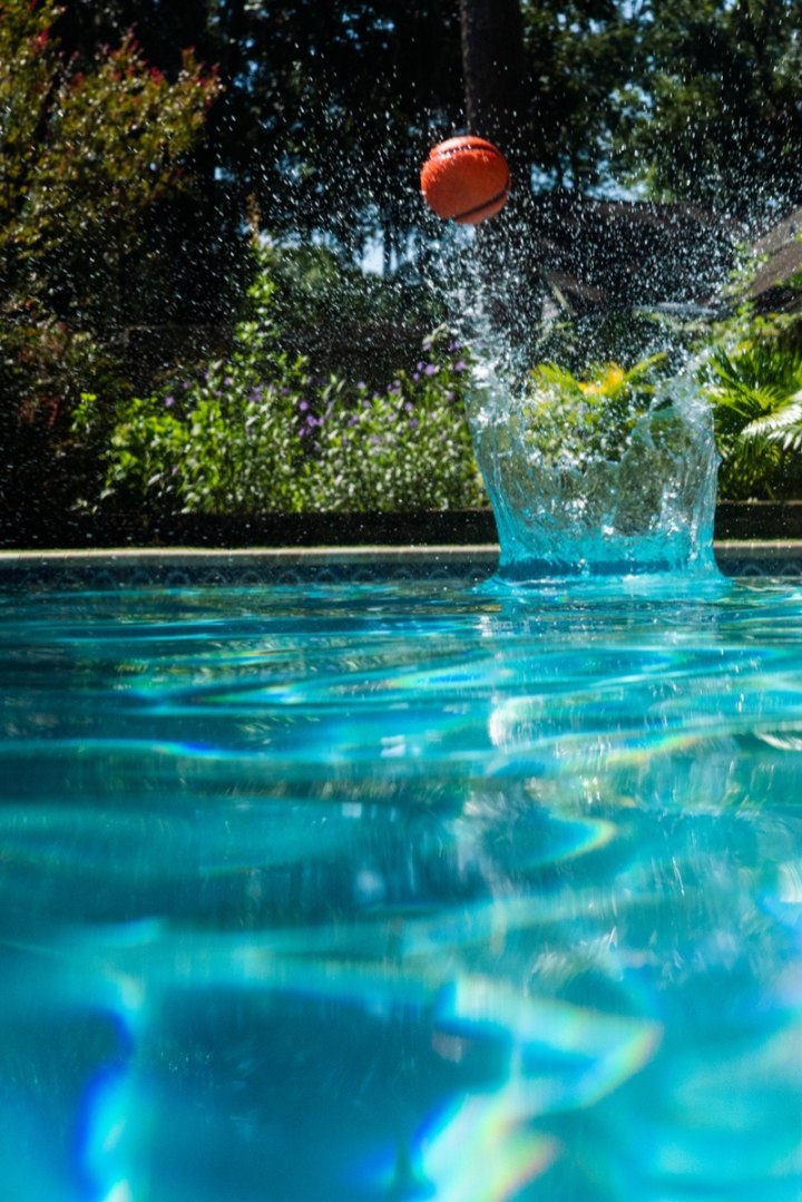 Pomarańczowa piłeczka Waboba ZAG odbijająca się nad niebieską wodą basenu w słoneczny dzień
