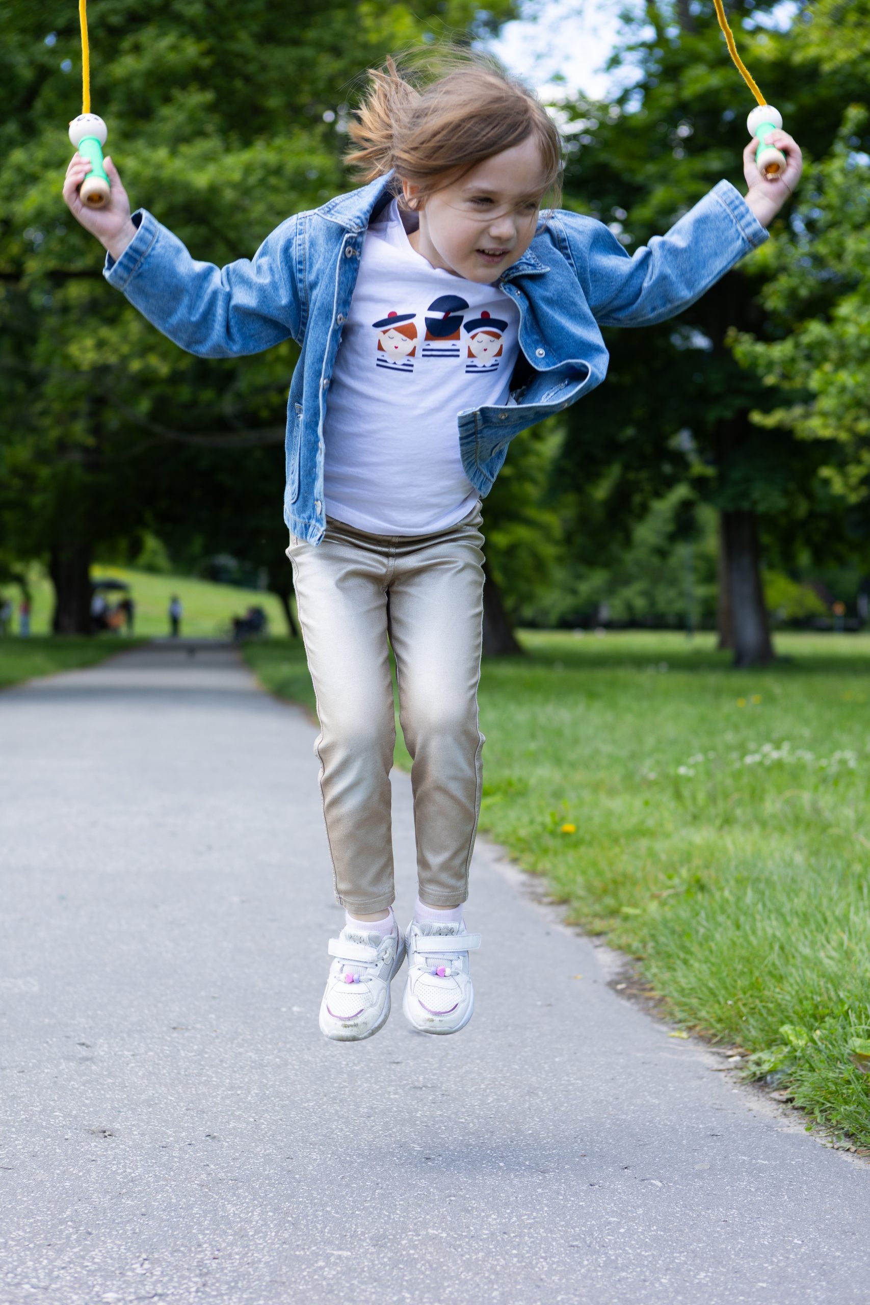 Dziewczynka skacze na świeżym powietrzu używając skakanki dla dzieci panda marki mideer