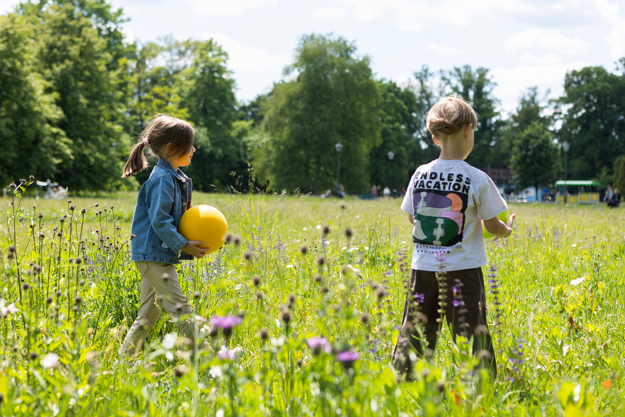 Dzieci bawiące się na łące z żółtą cichą piłką dla dzieci marki Yamann