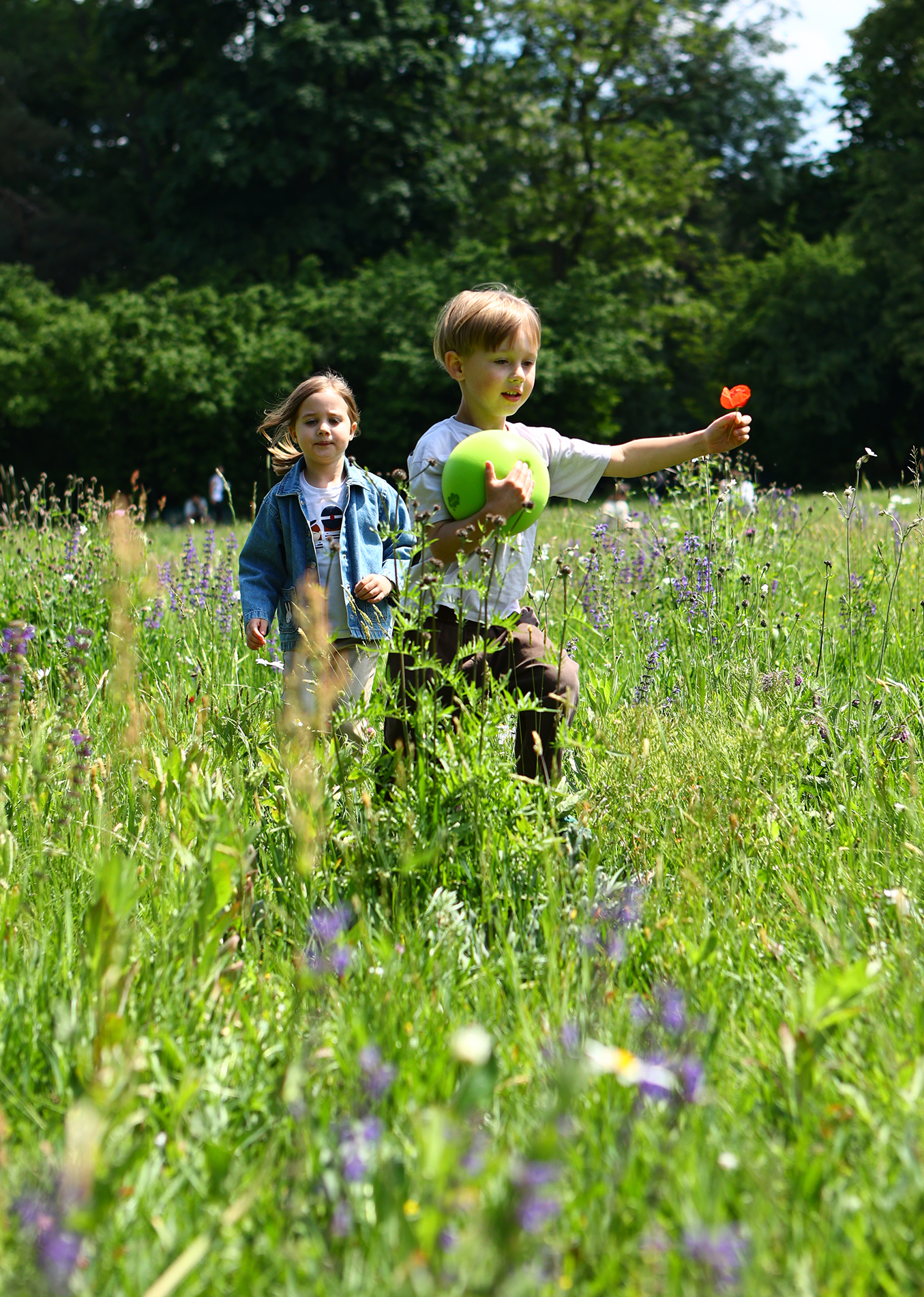 Dwoje dzieci bawiących się na łące z zieloną cichą piłką dla dzieci marki Yamann