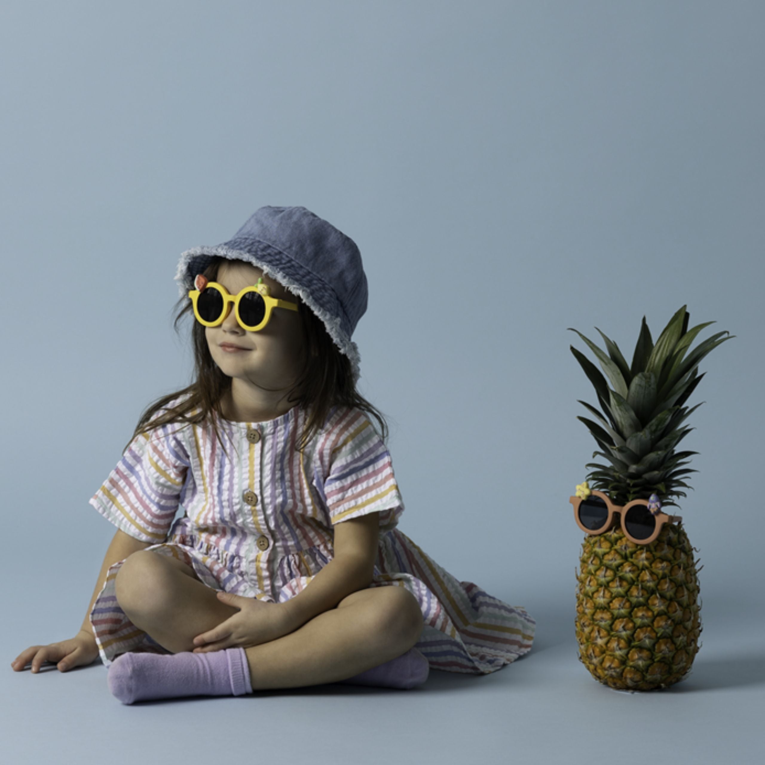Okulary przeciwsłoneczne dla dzieci w żółtej oprawce na dziewczynce i ananasie z okularami