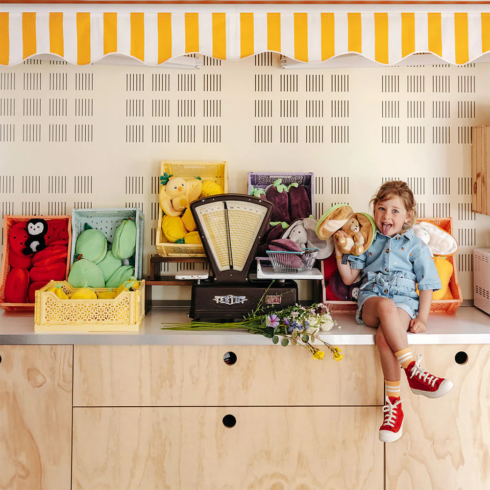 Maskotka pies jabłko przytulanka dla dzieci w kolorowym wnętrzu z dzieckiem siedzącym na blacie