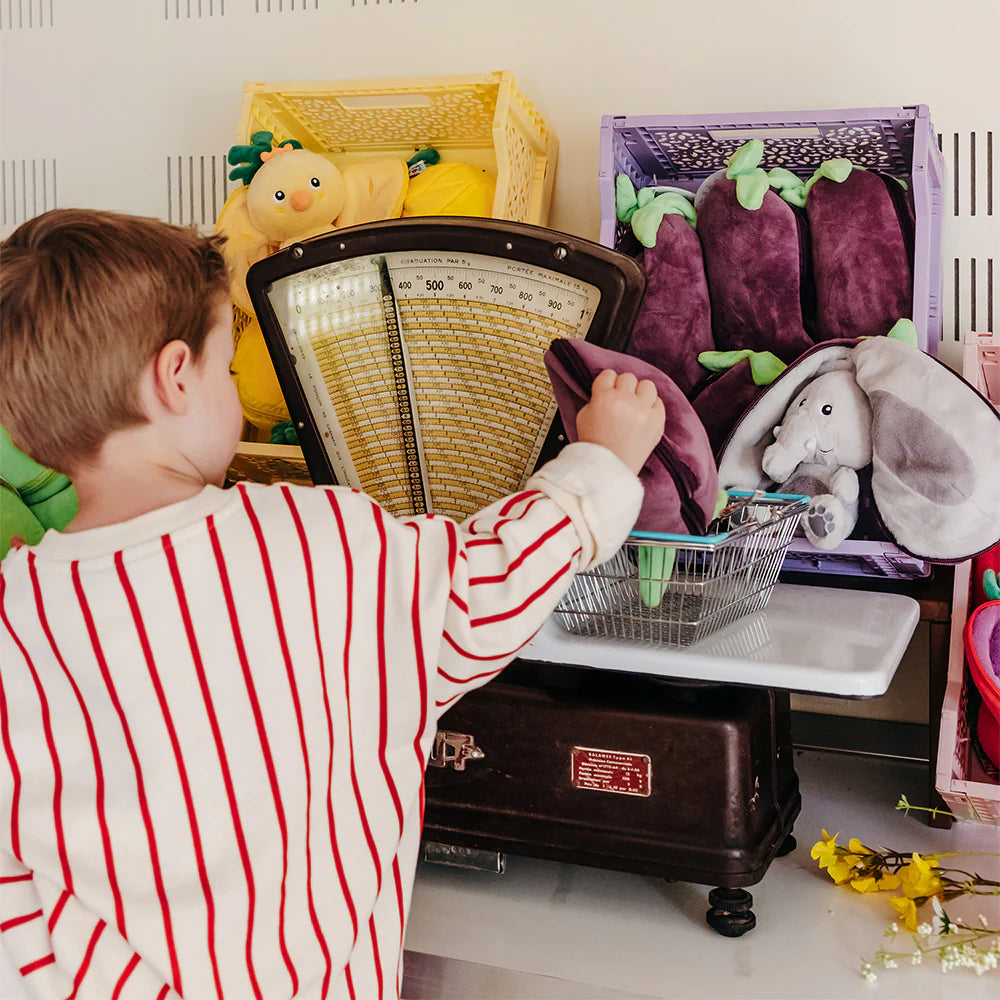 Dziecko bawiące się pluszakiem Flipetz słoń i bakłażan na starej wadze w sklepie