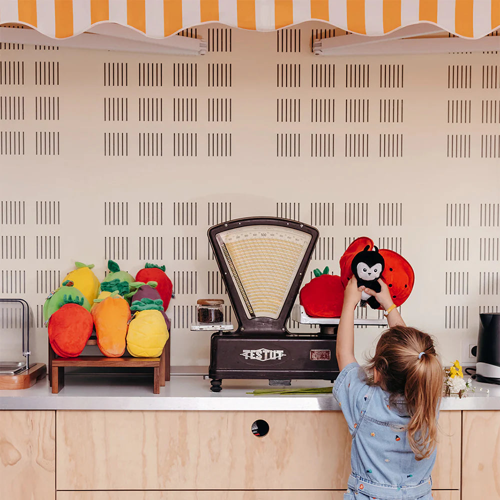 Dziecko trzymające pluszak Flipetz Biedronka i pomidor na kuchennym blacie z kolorowymi pluszakami owoców i warzyw