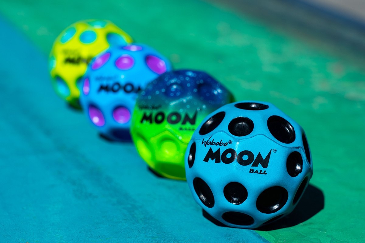 Żółta piłeczka Waboba Moon Ball żółta na zielonym tle z innymi kolorowymi piłeczkami Waboba Moon Ball