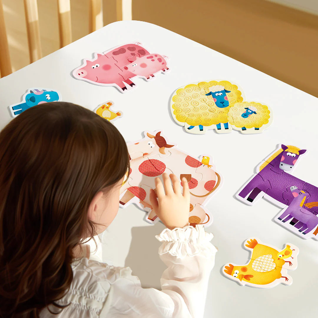 Dziecko układa pierwsze puzzle dla dzieci z kolorowymi zwierzętami na białym stole