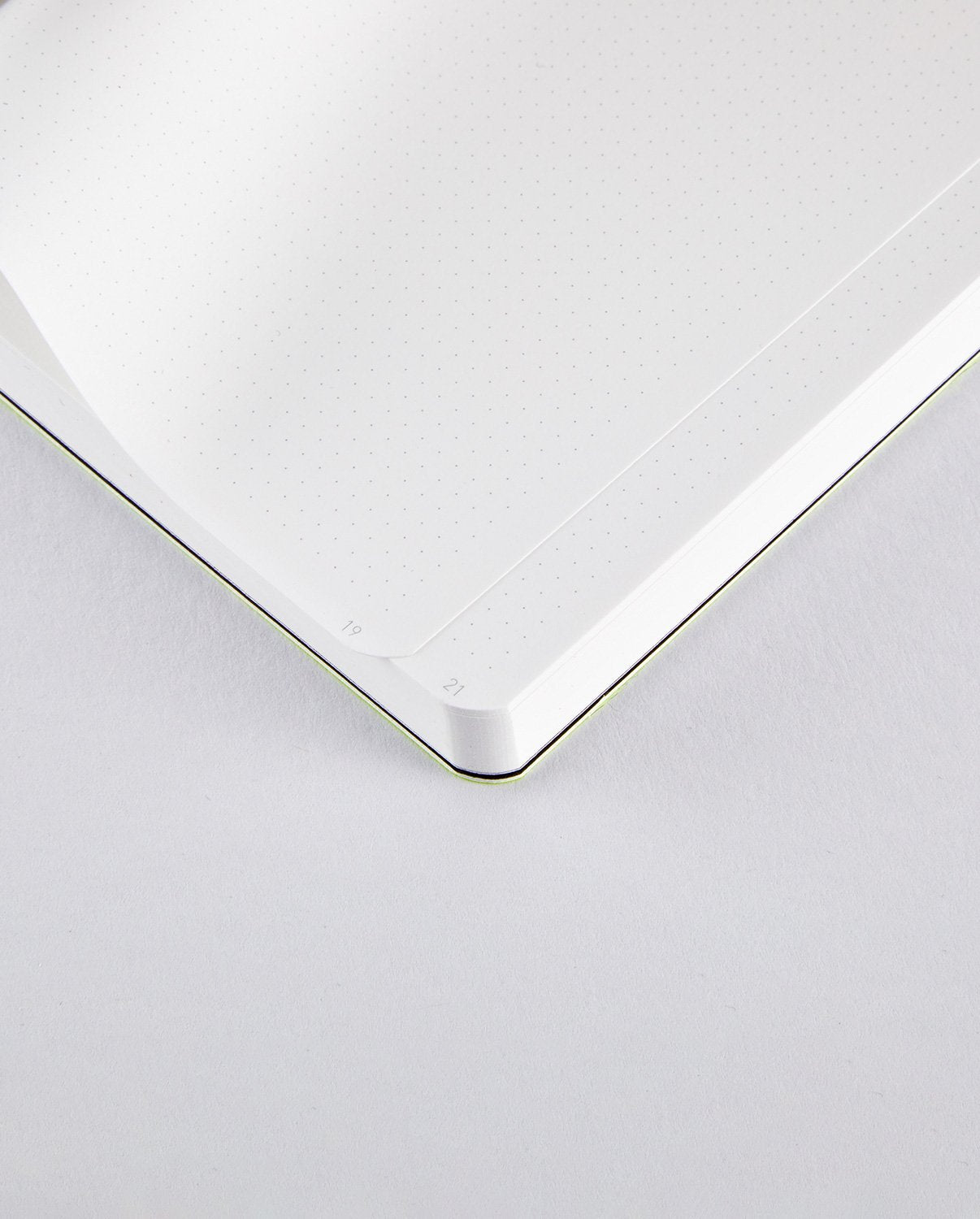 Otwarty notatnik neonowy żółty z delikatnymi kropkowanymi kartkami i zaokrąglonymi rogami