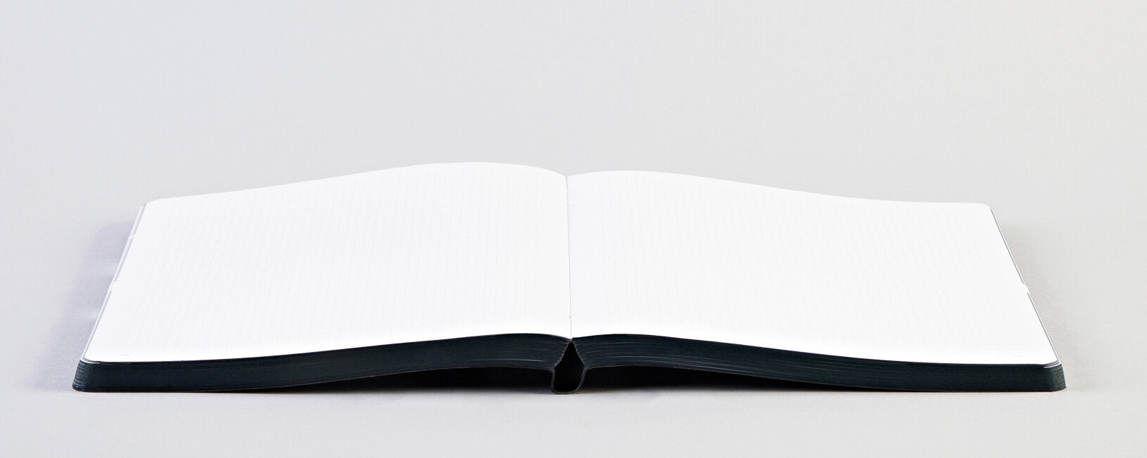 Otwarty notatnik graficzny z pustymi kartkami na szarym tle od BV JACOB COMPANY