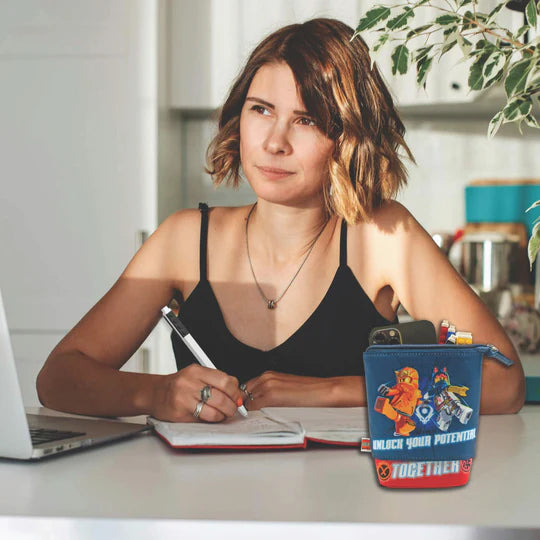 Piórnik LEGO Ninjago w niebieskim kolorze umieszczony na stole obok kobiety piszącej w notatniku