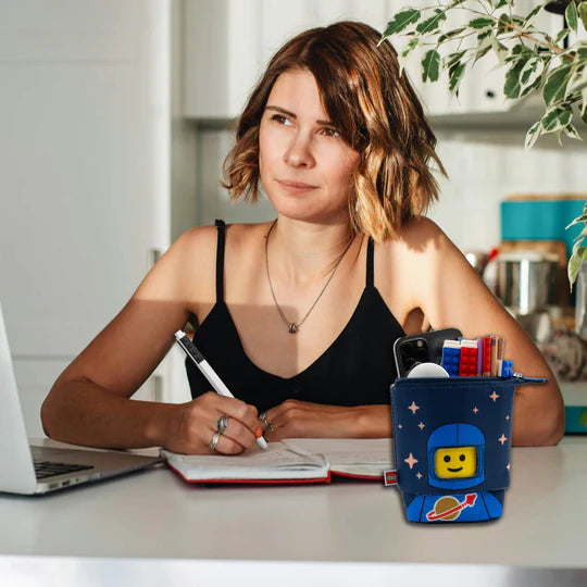 Piórnik LEGO astronauta niebieski z zabawną grafiką kosmonauty na biurku obok kobiety piszącej notatki