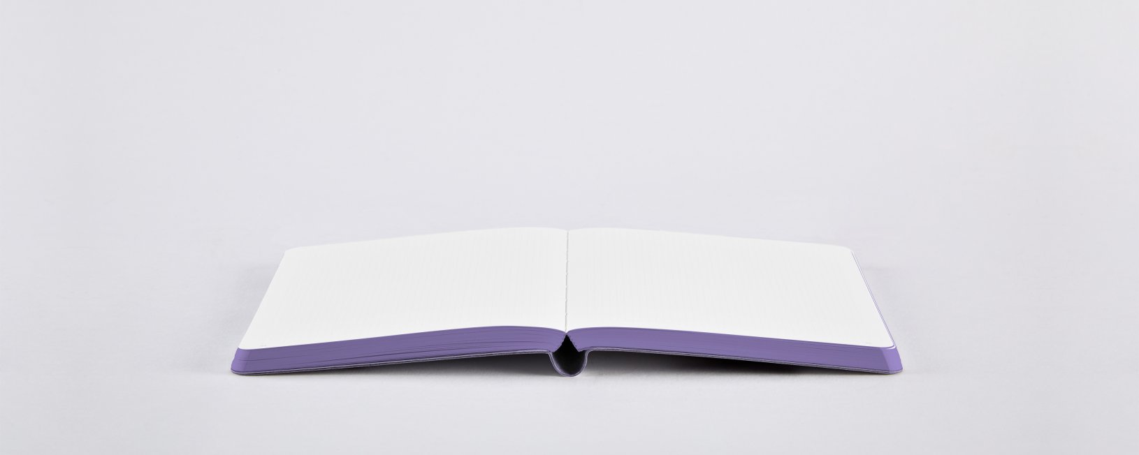 Otwarty notatnik z sercem z białymi kartkami i fioletową oprawą na białym tle