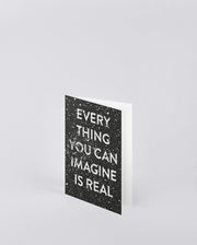 Czarna kartka okolicznościowa z cytatem Everything You Can Imagine Is Real na białym tle