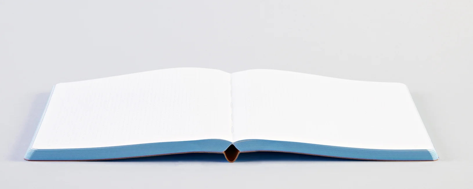 Otwarty notatnik Graphic L Unconditional Love z czystymi białymi kartkami na jasnym tle