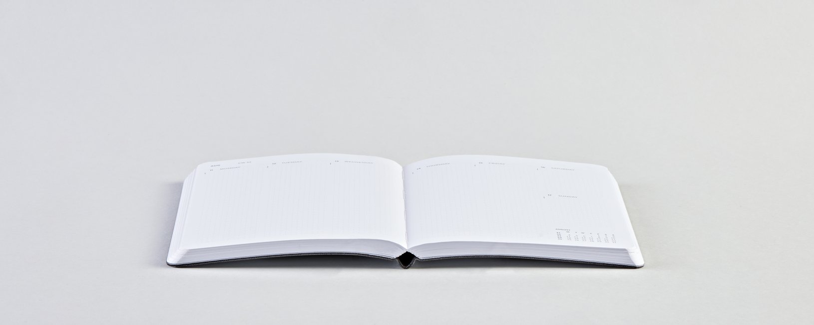 Biały kalendarz tygodniowy 2025 firmy BV JACOB COMPANY rozłożony na płasko na jasnym tle