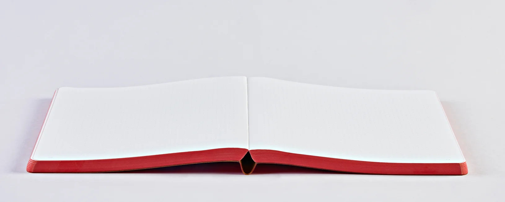 Otwarty notatnik truths & dares z czerwonym grzbietem i pustymi białymi stronami