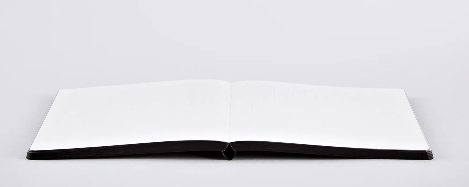 Otwarty notatnik w kratkę sassy squares z czarną oprawą na białym tle