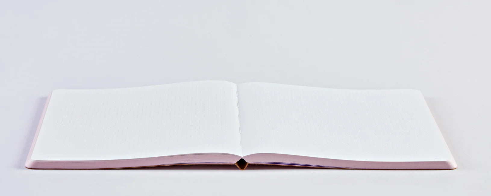 Notatnik trance pink otwarty na płaskim białym tle z czystymi, liniowanymi stronami
