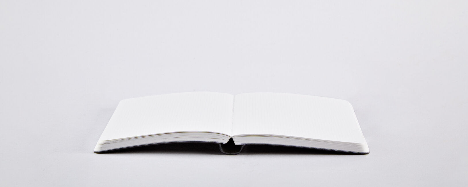 Otwarty biały notatnik Bébé Sucré S Glam Glam z pustymi stronami na jasnym tle