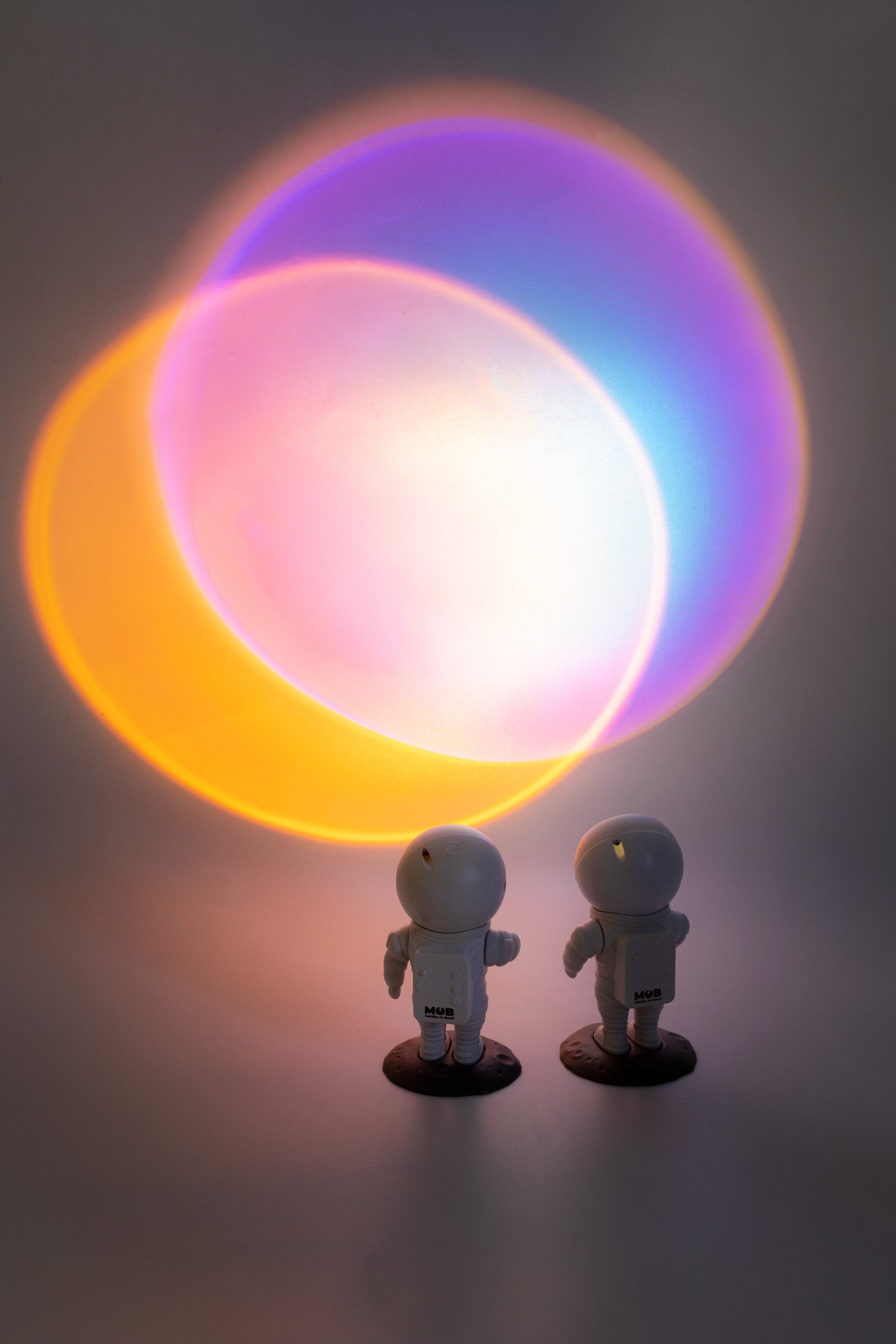Lampka projekcyjna astronauta rzucająca kolorowe światło na ścianę z dwoma figurkami astronautów