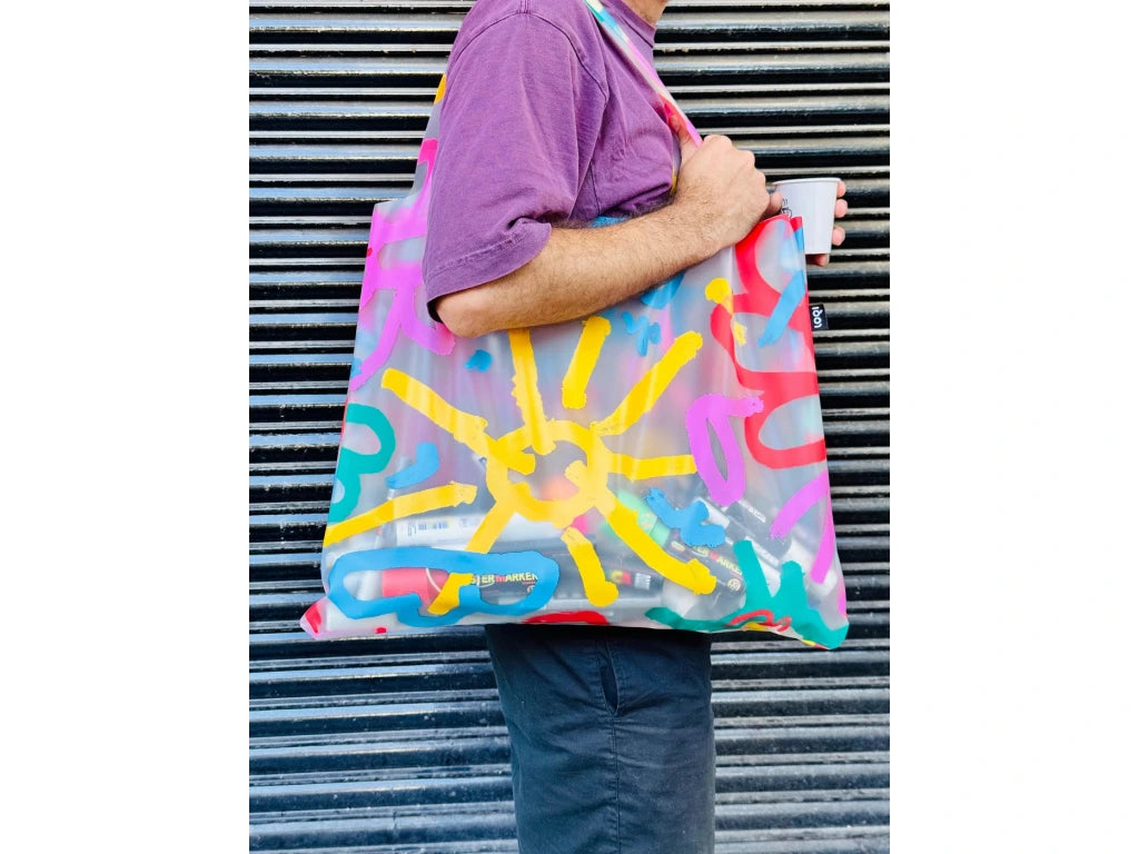 Kolorowa torba LOQI Bernardo Henning z abstrakcyjnym wzorem w słoneczne kształty noszona na ramieniu