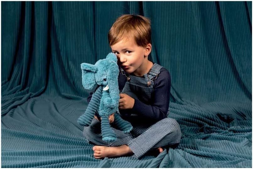 Dziecko bawiące się pluszowym słoniem niebieskim na niebieskim tle z tkaniny