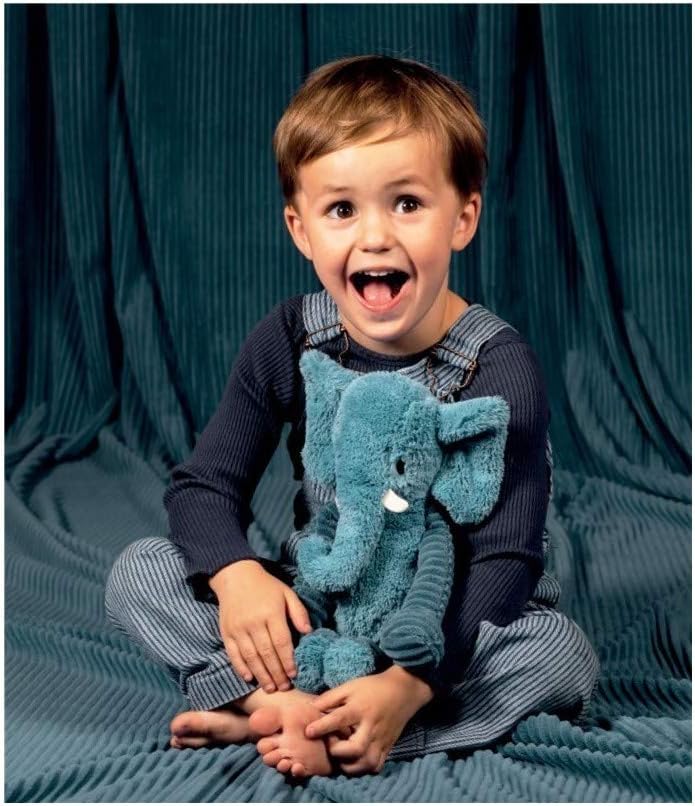 Chłopiec trzymający pluszowy słoń niebieski siedząc na miękkim kocu w pasy