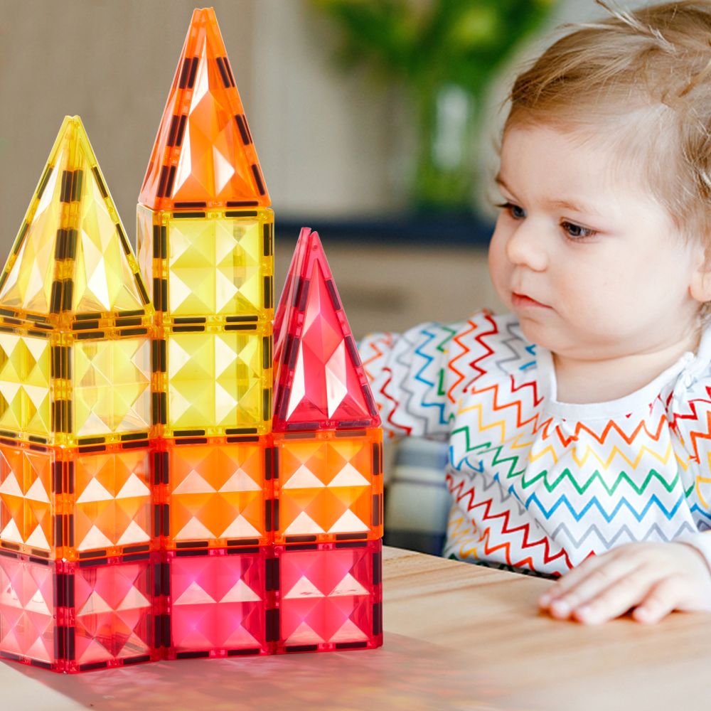 Dziecko bawi się kolorowymi klockami magnetycznymi dla dzieci tworząc zamek na stole