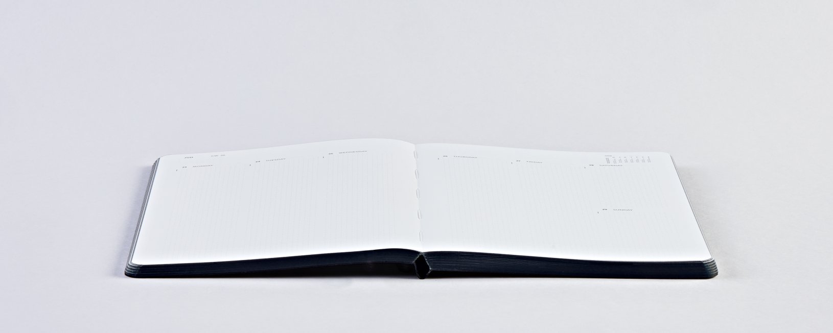 Otwarty kalendarz tygodniowy 2025 z czarną okładką na białym tle od BV JACOB COMPANY