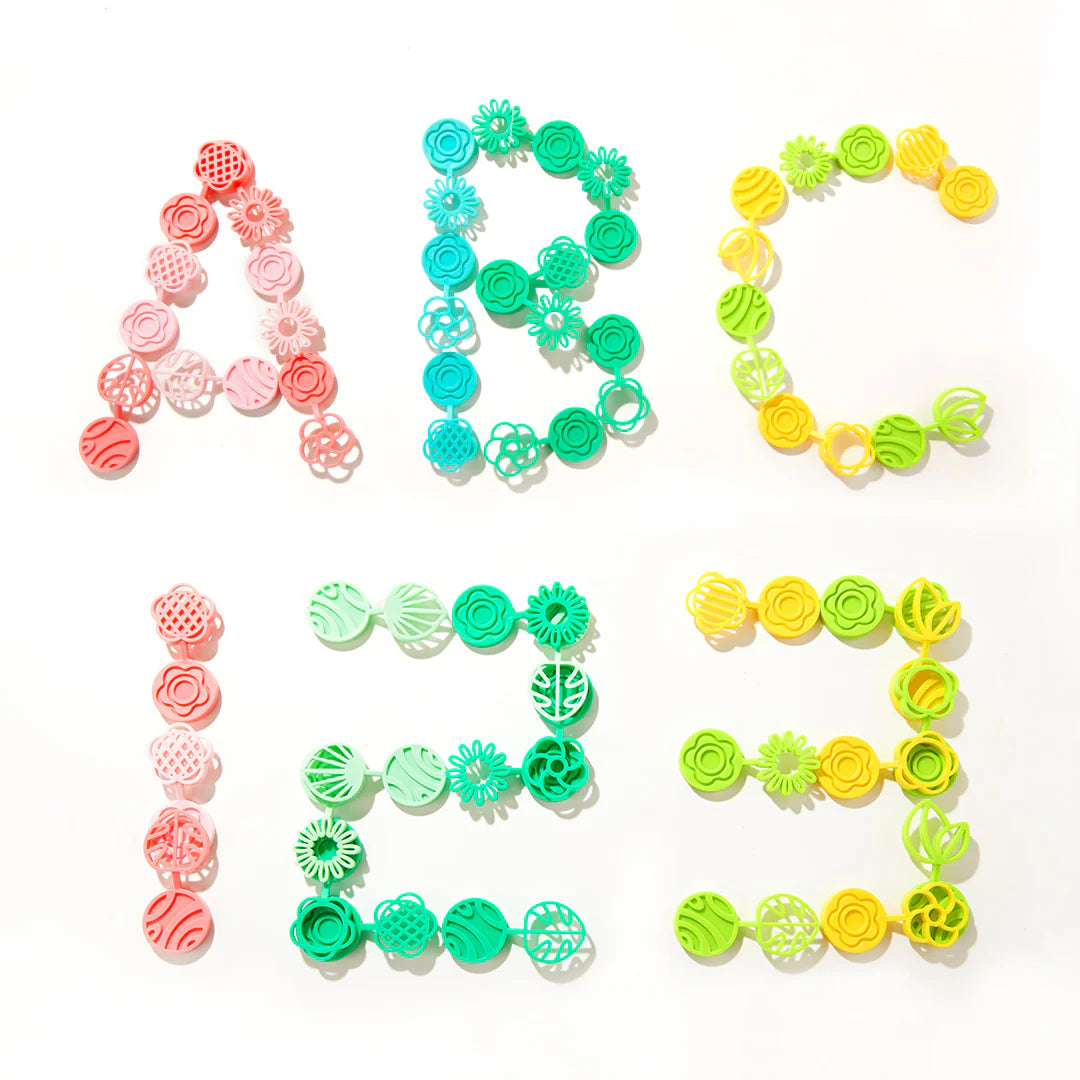 Kolorowe klocki edukacyjne dla dzieci ułożone w kształty liter A, B, C, 1, 2, 3 na białym tle