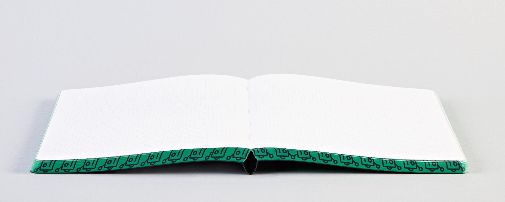 Otwarty notatnik Write Against The Machines z czystymi białymi kartkami i zielonym obramowaniem