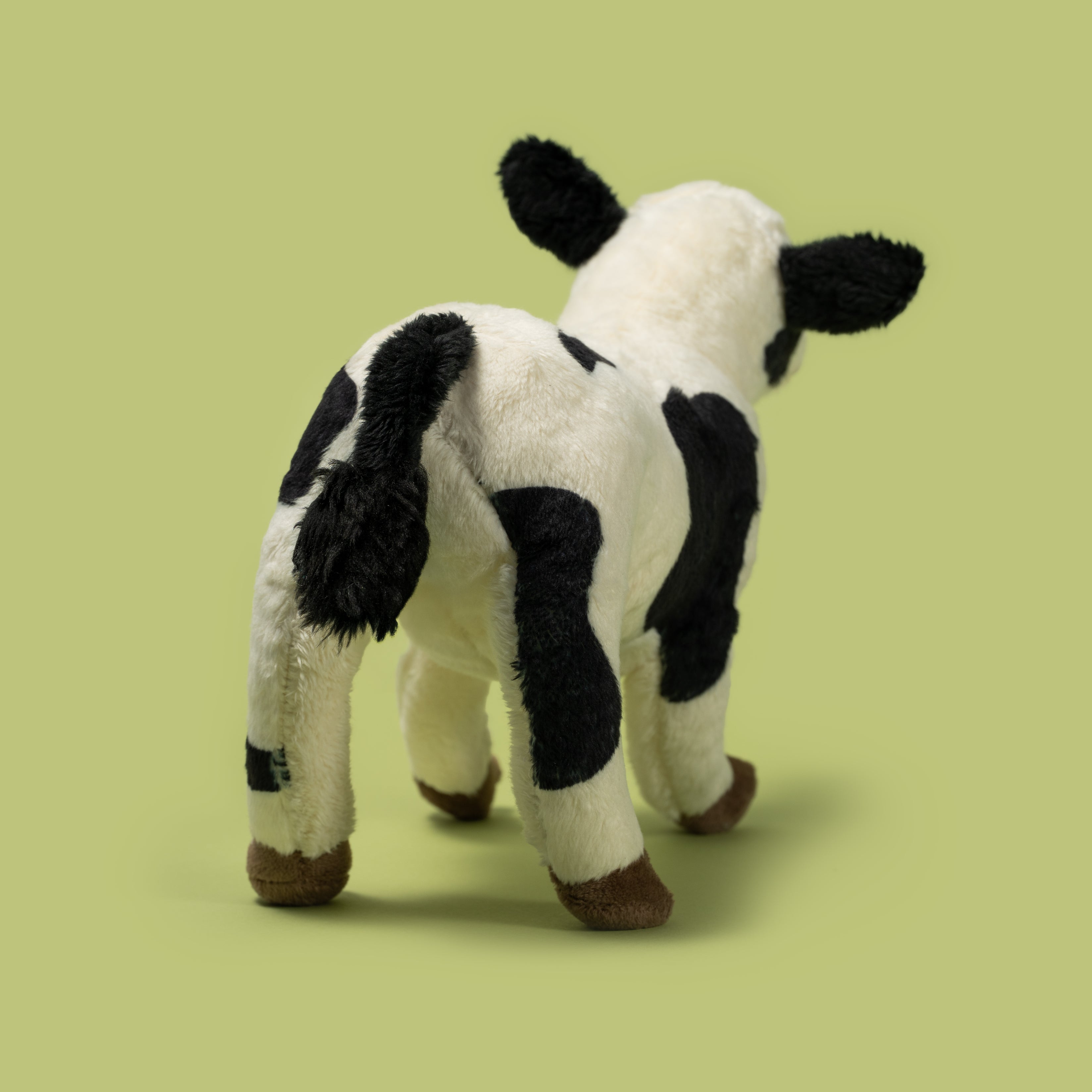 Pluszak ciele Wild Planet w biało-czarne łaty stojący na zielonym tle