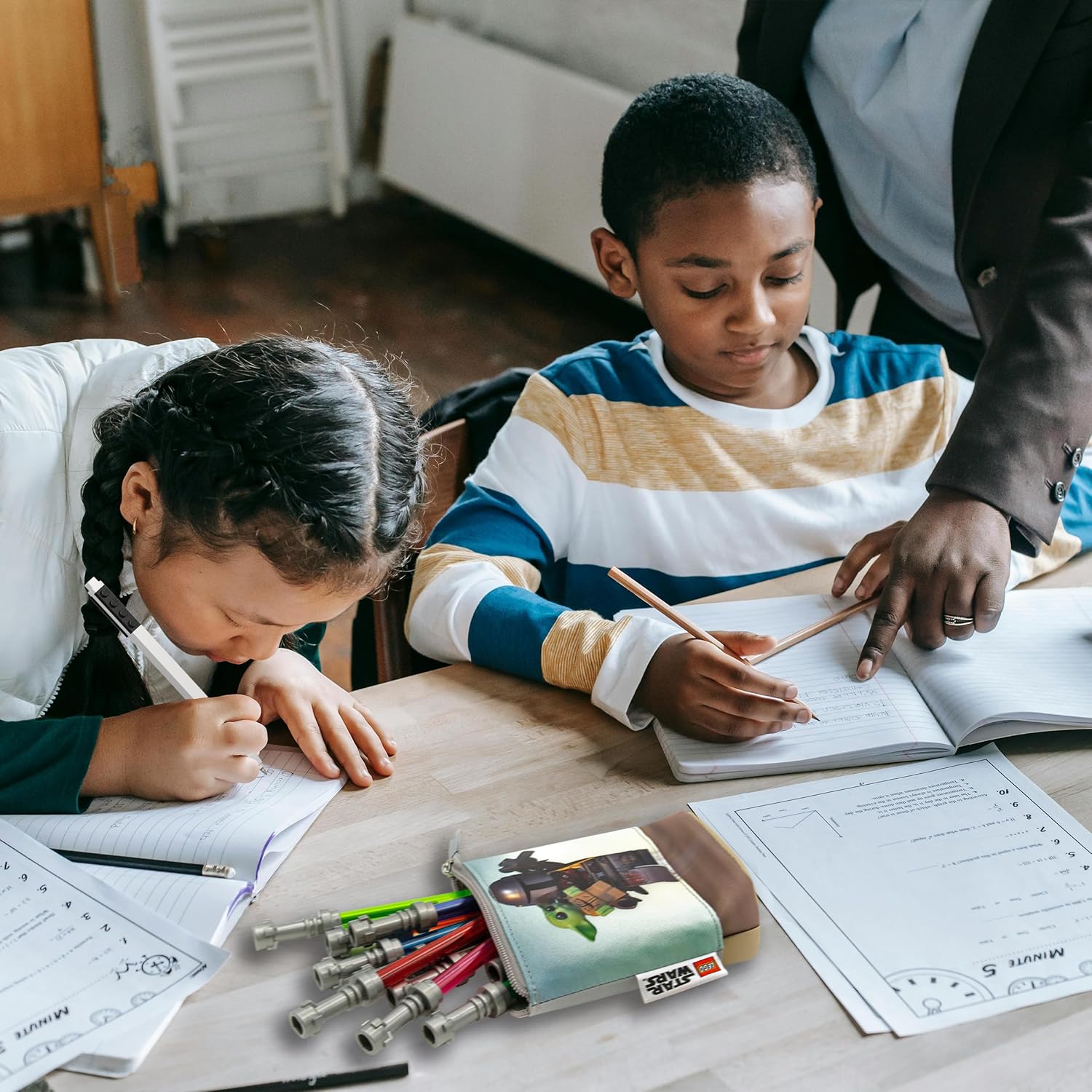 piórnik LEGO Star Wars Mandalorian na stole z przyborami szkolnymi obok dzieci piszących w zeszytach