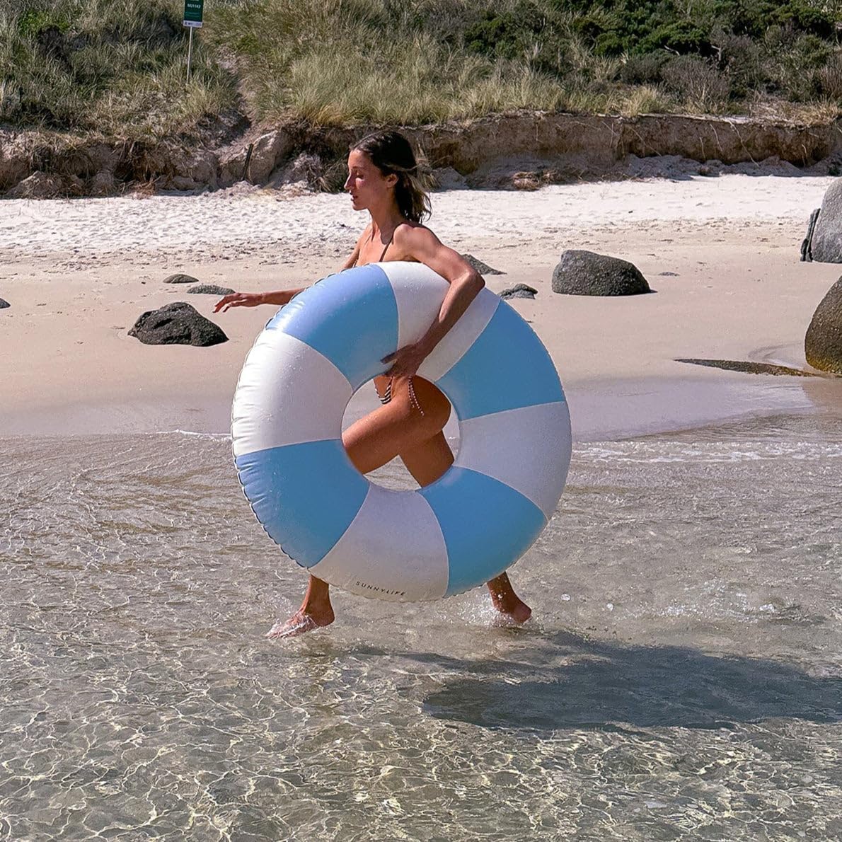 Kobieta biegnąca po plaży z niebiesko-białym kołem do pływania dla dorosłych od Yamann