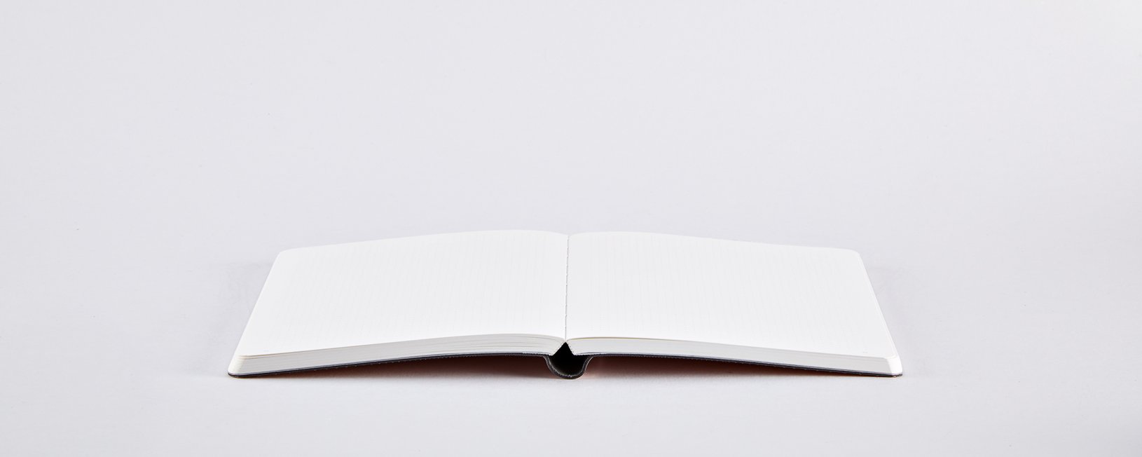 Notatnik różowy błyszczący otwarty na białym tle z pustymi kartkami do pisania