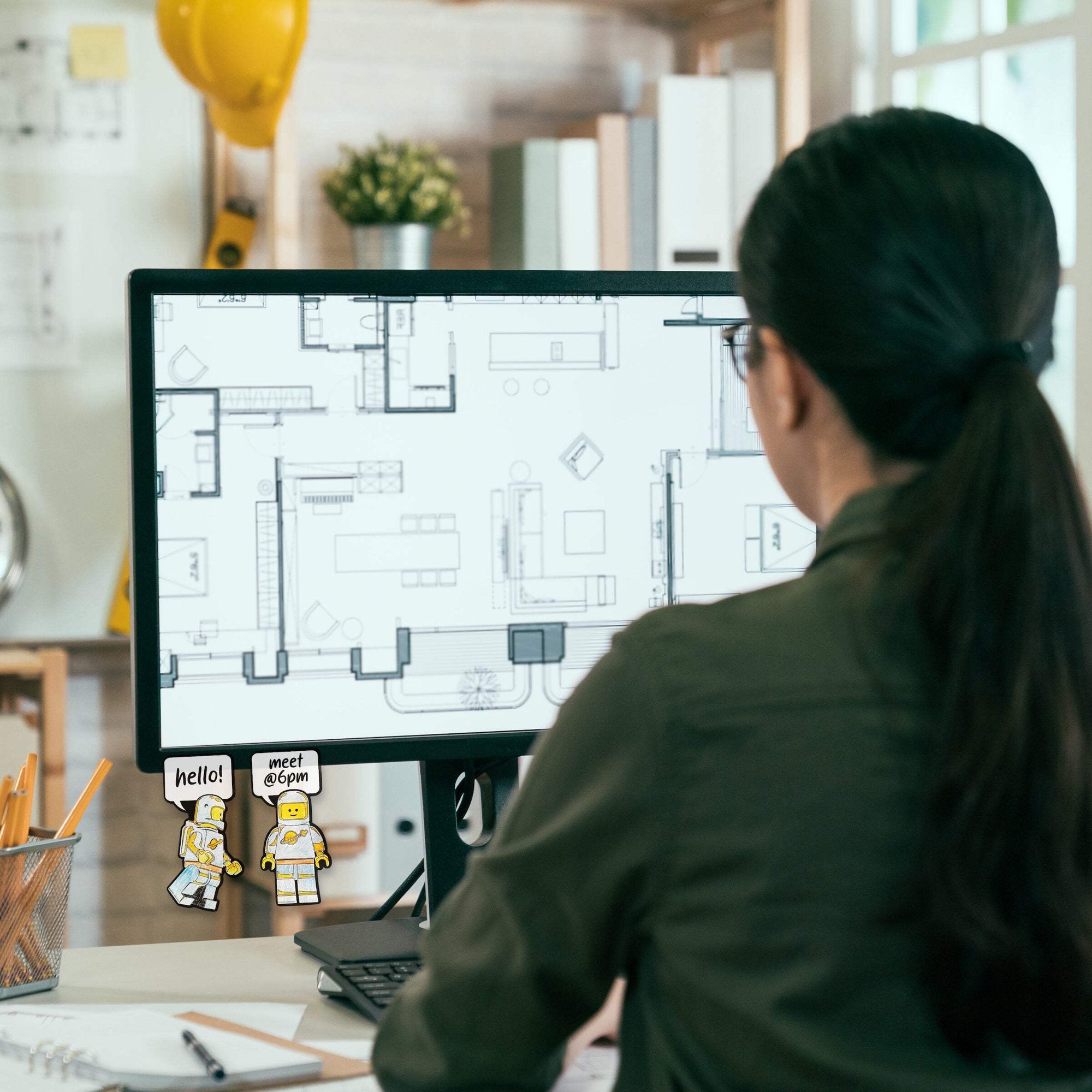 Kobieta pracująca przy biurku z komputerem ozdobionym samoprzylepnymi karteczkami LEGO kosmos w biurze