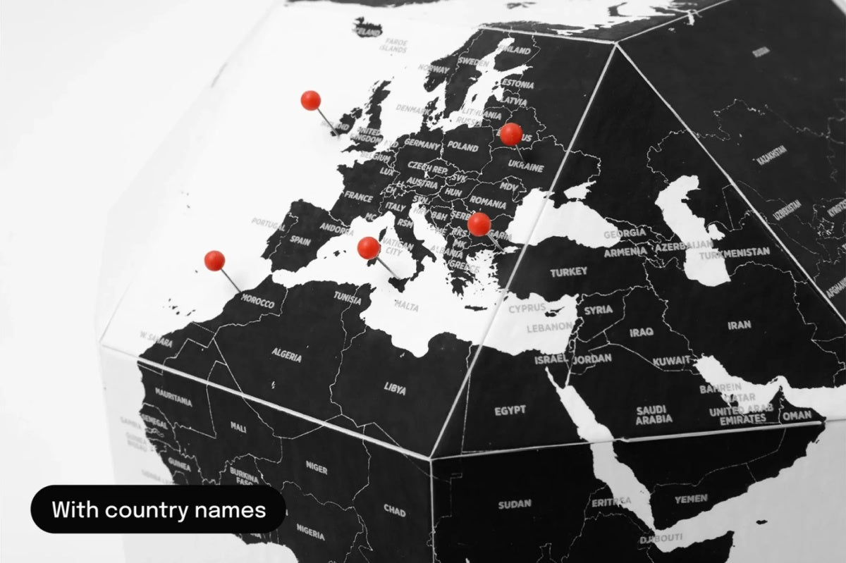 Czarny globus z pinezkami do oznaczania krajów na mapie Europy i Bliskiego Wschodu